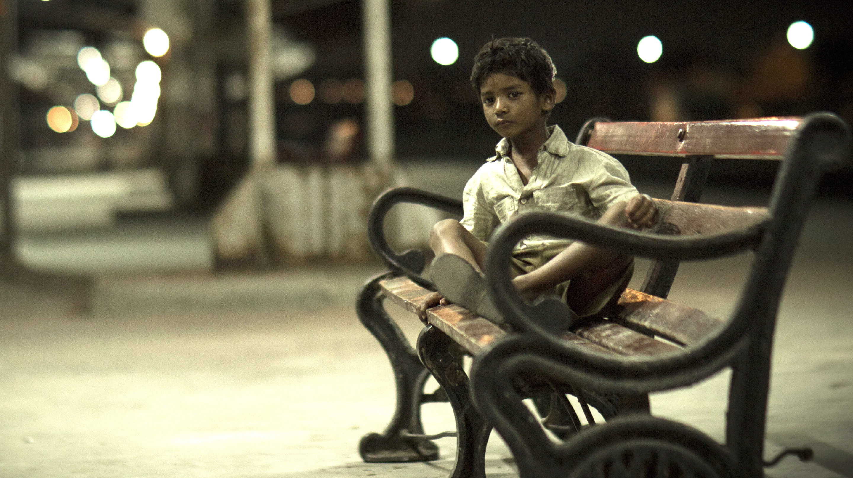 бедный индийский мальчик на скамейке на вокзале