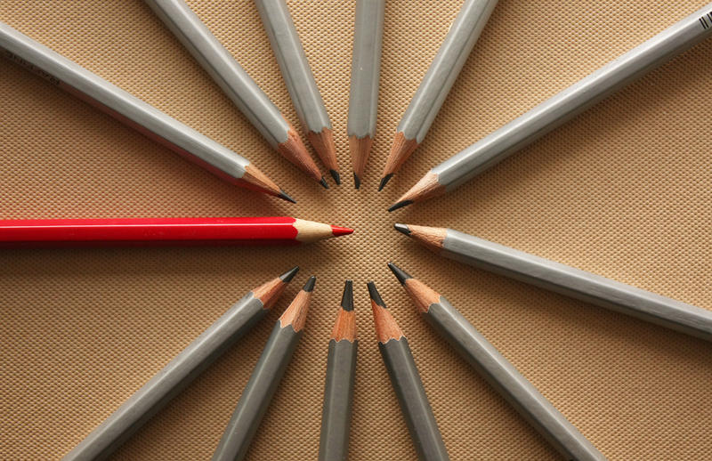 Серые и красный карандаши в кругу