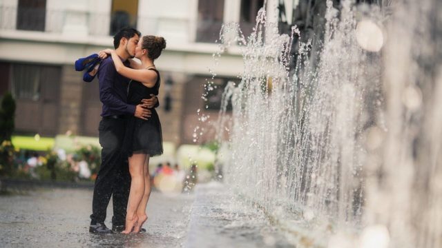 Пара целуется у фонтана