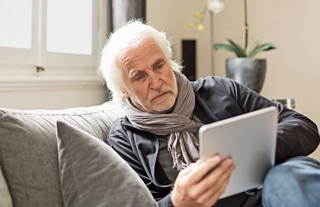 стильный пожилой мужчина смотрит в планшет