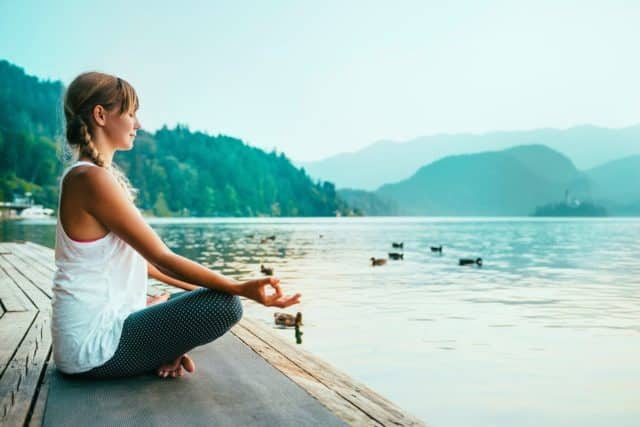 девушка медитирует на берегу озера