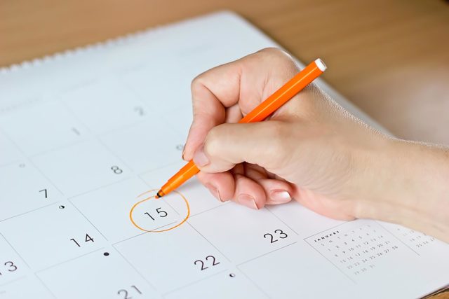 девушка обводит ручкой дату в календаре