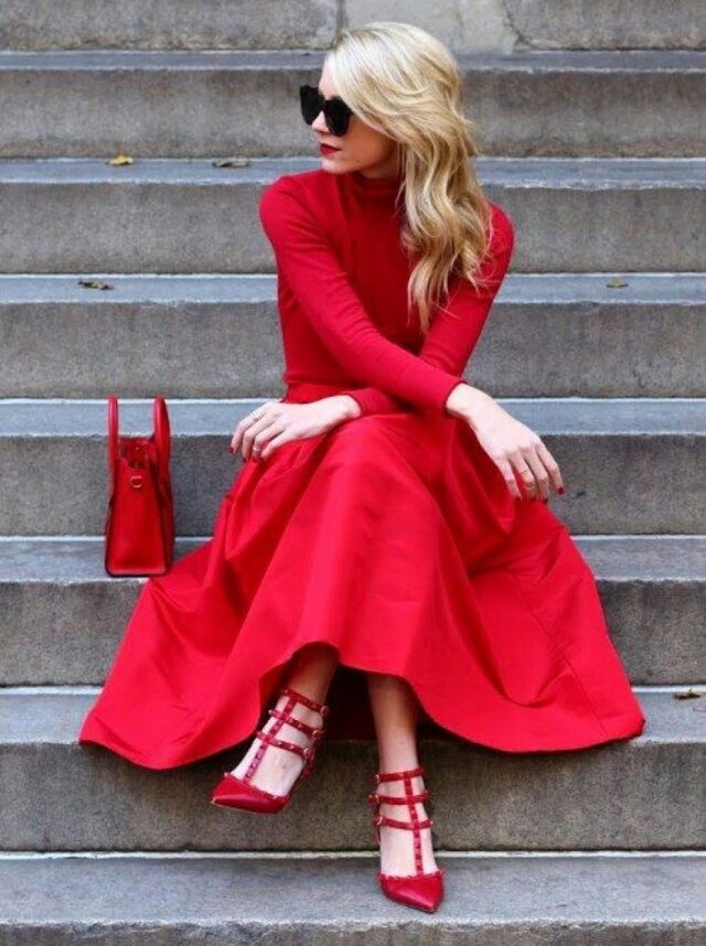 блондинка в красном платье сидит на ступеньках